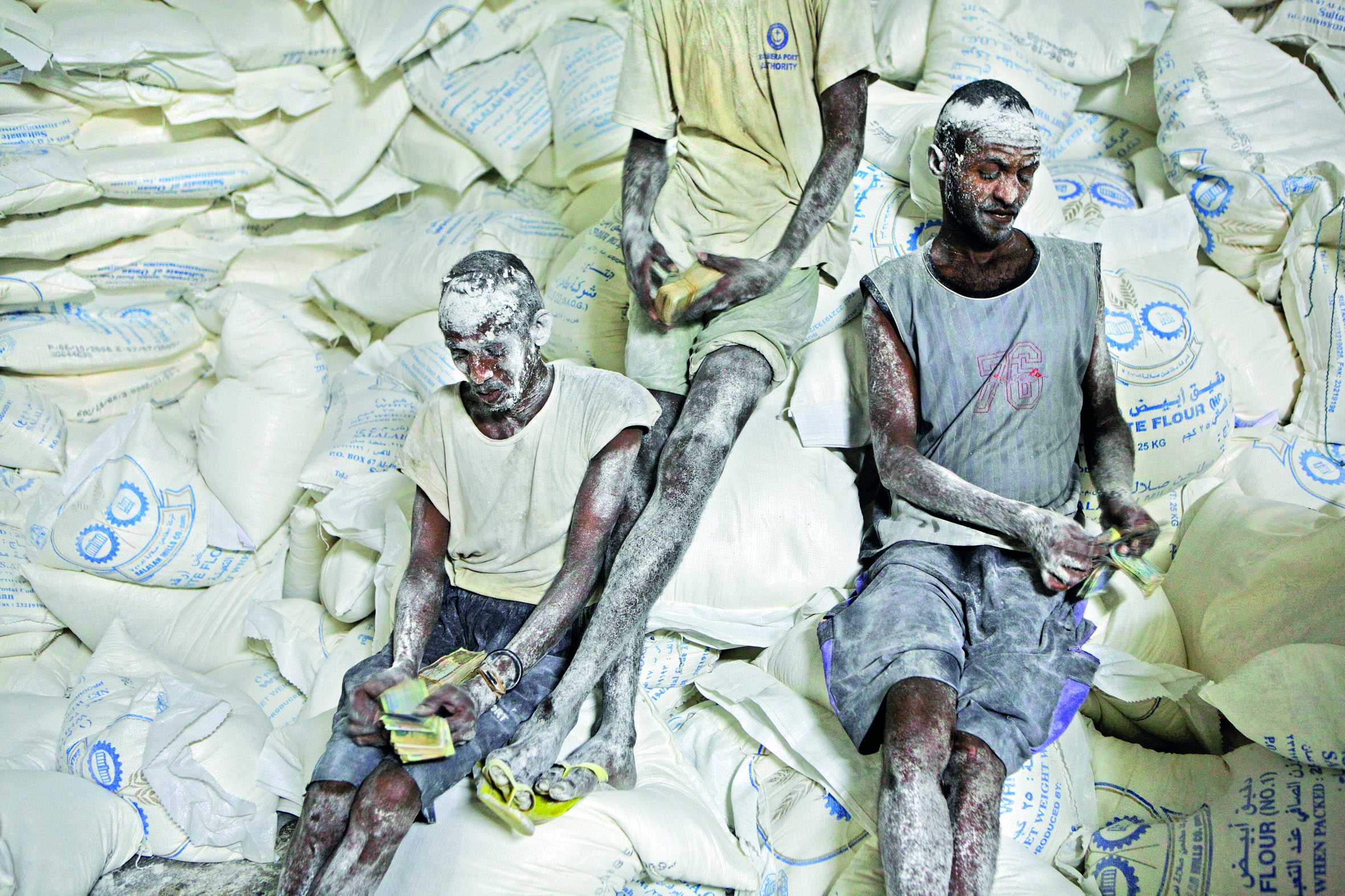 ©Pascal Maitre/National Geographic Il riposo degli scaricatori Operai contano la paga dopo aver scaricato un camion di farina in Somalia
