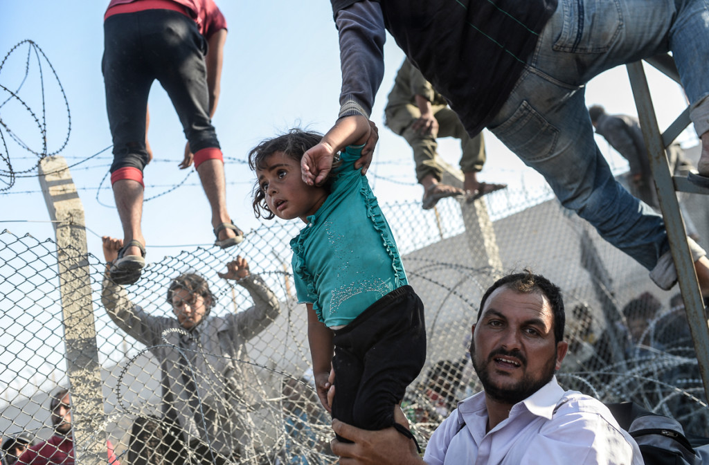 14 giugno 2015. Migliaia di Siriani provano a oltrepassare le recinzioni e a entrare illegalmente in Turchia dopo aver appreso che i combattenti curdi si stanno avvicinando al Turkish Arkcakale. © AFP/Bülent Kiliç
