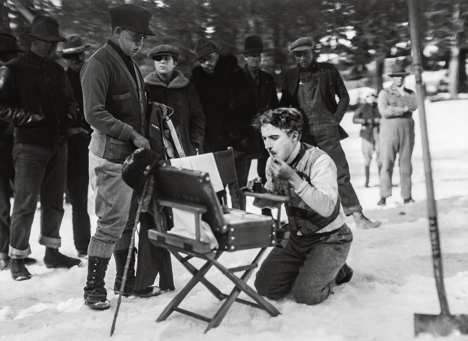 Chaplin alle prese con il trucco di scena durante le riprese del film La febbre dell'oro (1925). © Roy Export Company Establishment.