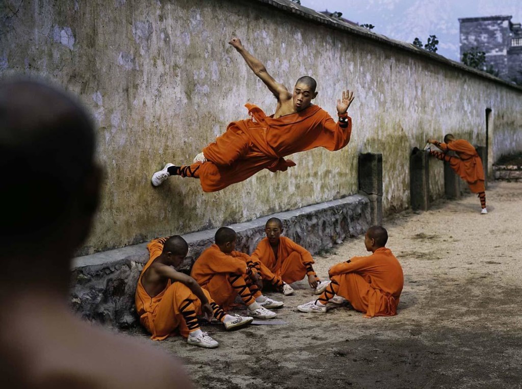 Steve McCurry: A young monk runs along the wall over his peers. Hunan Province, China, 2004. ©Steve McCurry.