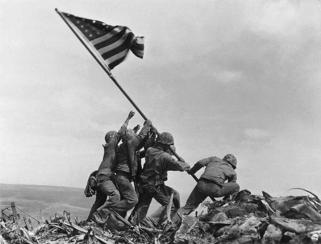 “La bandiera è issata su Iwo Jima”. Il momento in cui la bandiera americana è piantata sul monte Suribachi. Da sinistra a destra: Pvt 1st Class Ira H. Hayes; Pvt 1st Class Franklin Sousley, (KIA); Sgt Michael Strank, Pharmacist Mate 2/c John H. Bradley; Pvt 1st Class Rene A. Gagnon and Cpl Harlon H. Block, (KIA). Iwo Jima, 23 febbraio 1945, foto di Joe Rosenthal, courtesy U.S. Marine Corps. 