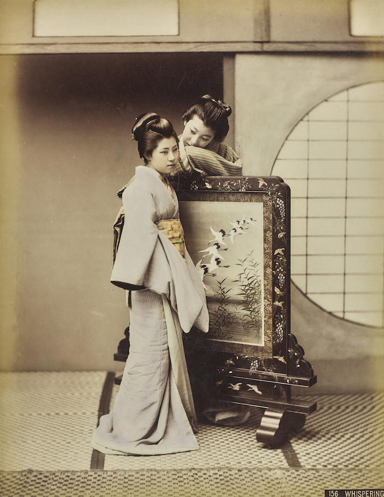 Kusakabe Kimbei, Whispering. Conversazione sussurrata tra due geishe accanto  a un paravento, 1885-1895 �Raccolte Museali Fratelli Alinari (RMFA), Firenze 