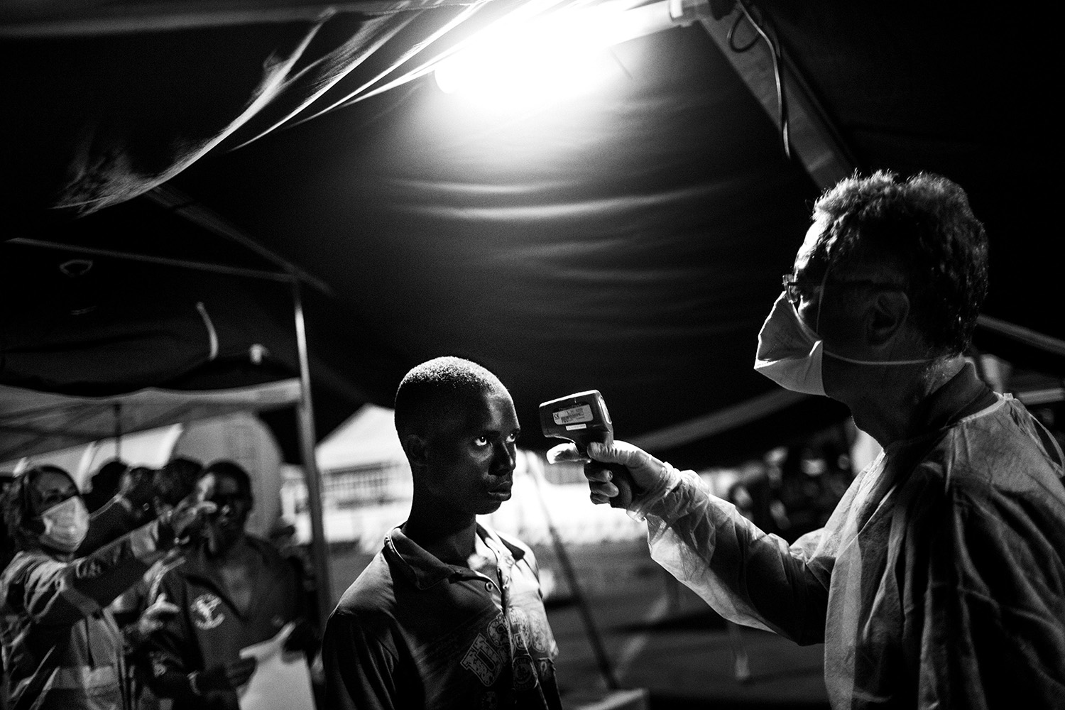 An Italian Red Cross doctor measures - with an electronic thermometer - the temperature of a Sub-Saharan boy, during the medical check in the tent set up at the dock in the port of Messina (Italy). On July 31st 2015, 392 people were disembarked from the Italian Coast Guard ship Diciotti at the Sicilian port of Messina. Most of the people came from Sub-Saharan countries like Gambia, Senegal, Mali, Ivory Coast, Togo, Ghana, Cameroon, Nigeria, Burkina Faso, Guinea Conakry and Guinea Bissau. There were also refugees coming from Sudan, Somalia and Libya.
