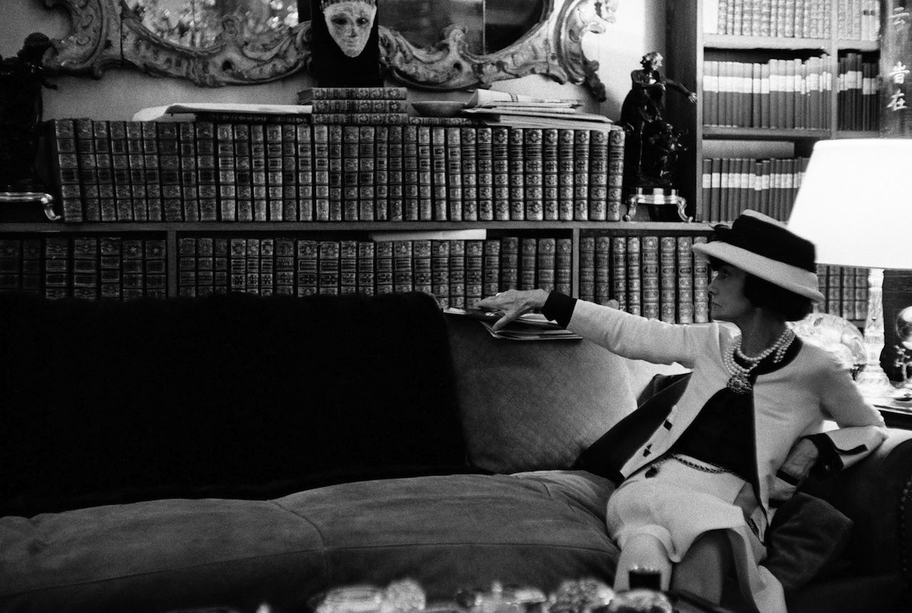 Douglas Kirkland Ritratto di Gabrielle Chanel sul suo divano, mentre guarda la sua biblioteca, luglio 1962 Fotografia Collezione Douglas Kirkland, Los Angeles © Douglas Kirkland 