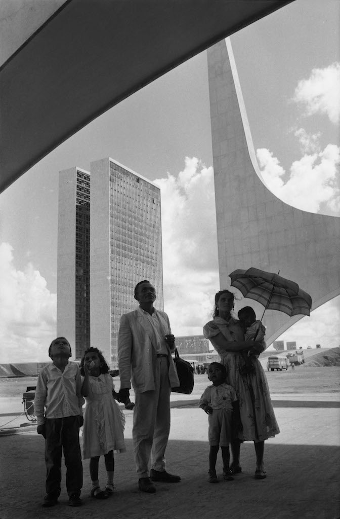 René Burri, A worker from Nordeste shows his family the new city on inauguration day. In the background: the National Congress building by Oscar Niemeyer. Brasilia, Brazil, 1960 © René Burri / Magnum Photos