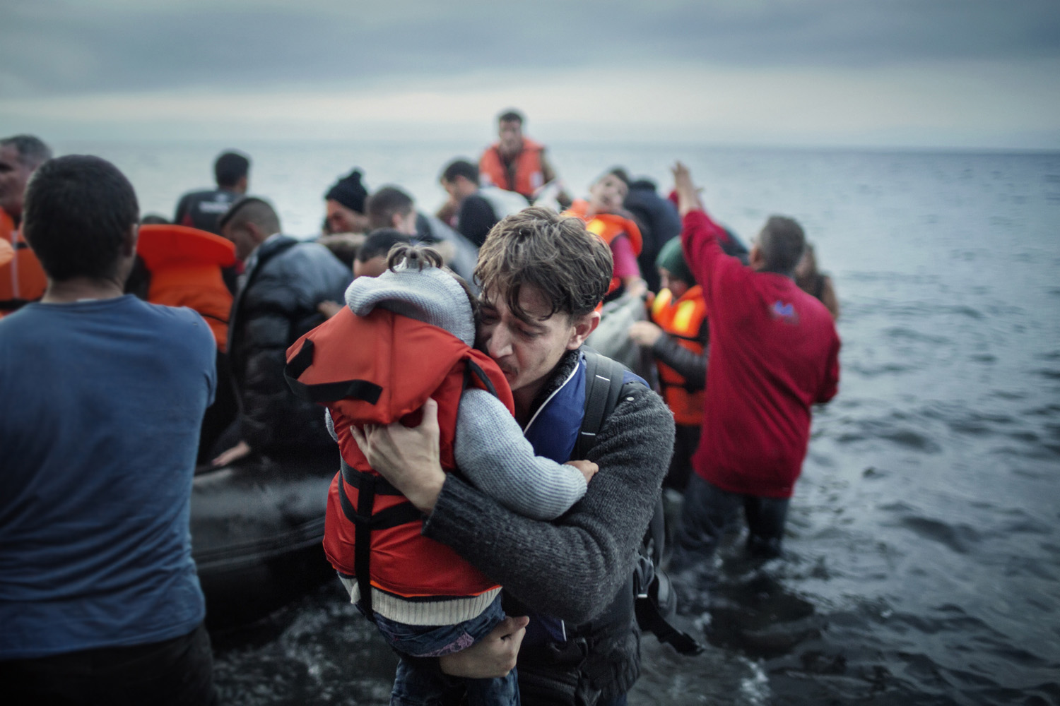 Lesbos. Greece. Oct. 21, 2015.  A  father hugs his young daughter as they land on the Greek island of Lesbos,  after crossing the Aegean sea from the Turkish coast  He later said they were afraid during the trip because of the bad weather.According to UNHCR, approximately 850,000 refugees and migrants, including children, arrived in Greece by sea in 2015. Of these, just over 500,000 landed on Lesbos, a Greek island around eight nautical miles from the Turkish coast.  Although at the centre of migration flows, Lesbos had nothing to offer the mainly Syrian, Afghan and Iraqi refugees, asylum seekers and migrants who arrived there. Once they reached Europe’s beaches, they were welcomed with a long trek across the island’s mountainous interior, followed by days and nights spent in crowded refugee camps, where not even a place in a tent was guaranteed and where basic amenities such as toilets and showers were lacking. © Alessandro Penso