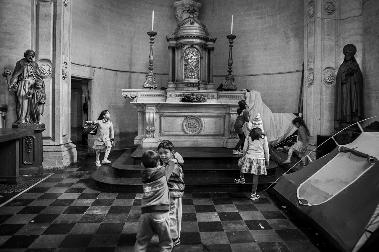 Bambini rifugiati afghani giocano nell’abside della chiesa occupata di Saint J. B. au Béguinage a Bruxelles, nella quale vivono da qualche settimana. © Alberto Campi
