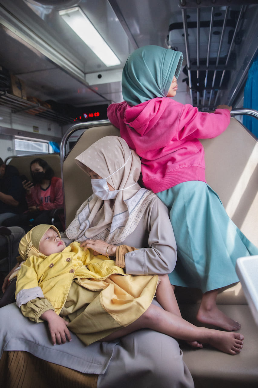 Una famiglia indonesiana in un vagone di prima classe con aria condizionata su un treno che va da Tegal a Yogyakarta, Java. Indonesia, 2022 - Umidità 80%, Temperatura 25°C